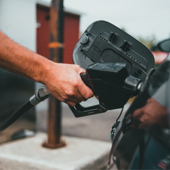 A close-up of a hand filling up their car's gas tank