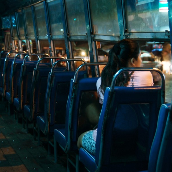 A woman rides a bus alone at night
